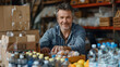 © garpinina - uomo maturo che lavora come volontario presso il centro comunitario e sistema cibo e acqua donati in scatole