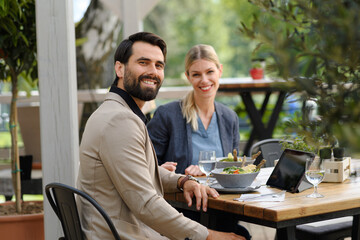 Business lunch for two managers, discussing new business project. Couple sitting outdoors on terrace restaurant, having dinner date.