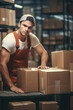 © vefimov - Man in orange apron stands in front of stack of boxes