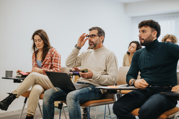 A diverse group of adult learners participate in a class discussion, exhibiting focus, engagement, and collaboration.