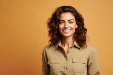 Wall Mural - Portrait of smiling woman in khaki shirt on orange background.