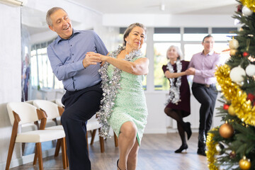 Wall Mural - Happy caucasian adult man and lady dancing rock and roll dance in modern dance studio during celebration Christmas and New Year