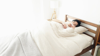 寝ながら体温計で熱を測る男性