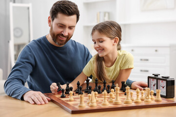 Wall Mural - Father teaching his daughter to play chess at home