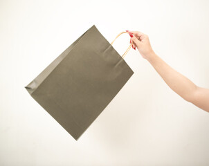 hand holding a shopping paper bag against a white isolated background