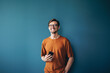 © Jacob Lund - Business man holding a smartphone and standing against a blue wall in a banking company