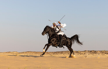 Wall Mural - Horseback archery in a desert of Saudi Arabia