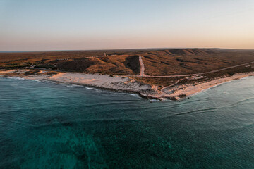 Wall Mural - Aerial picture of a sunset over the lighthouse in Exmouth, Western Australia. Beach and ocean view from the sky. Transparent water. Ningaloo reef, Australia.