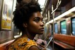African woman with a serious face sits on a deserted metro train. Tired young female riding in a subway at late hours.