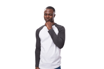 young handsome african guy dressed in a sweatshirt stands thoughtfully on a white background with copy space