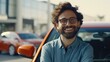 A man with glasses and a beard standing in front of a car. Suitable for automotive industry promotions