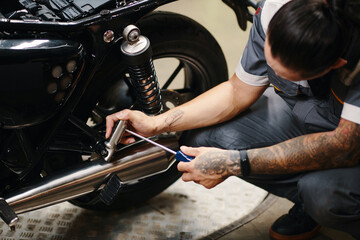 Wall Mural - Garage worker repairing motorcycle of client