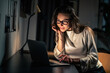 © zinkevych - Woman using laptop for remote working at home at night in dark room