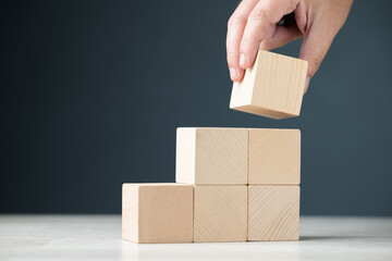 Fototapete - Hand arranges wood cubes by stacking up as step stairs, growth, and development, step process, build success concept