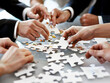 There are puzzles with different ideas and concepts scattered on the table. A group of people are working together to try to fit the puzzles into a coherent picture. Teamwork. Brainstorming concept.