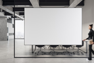 Canvas Print - Young woman walking in modern concrete meeting room office interior with empty white mock up banner. Workplace ad concept.