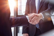 executives shaking hands in front of their manager and a colleague