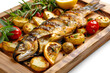 Roasted fish and potatoes, served on wooden tray, isolated on white