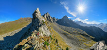 Austria, Tyrol, Sun shining over female hiker following Aschaffenburger Hohenweg trail in Zillertal Alps