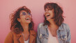 © Daria - Two friends laughing heartily, pink background, moments of joy and friendship