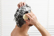 © New Africa - Man washing his hair with solid shampoo bar in shower, closeup