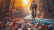 Cyclist on a scenic autumn road with fallen leaves and golden sunlight filtering through the trees.