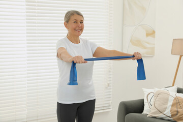 Poster - Senior woman doing exercise with fitness elastic band at home