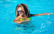 Pretty woman in a bright swimsuit and curly hair doing fitness in the turquoise swimming pool waters in Jurmala, Latvia	