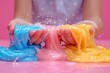© Irina Mikhailichenko - Kids hands making slime toy on pink background. Kids hands playing slime toy. Making slime. Copyspace. Selective focus