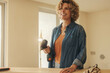 Woman smiling and holding a drill tool during a home kitchen remodeling project