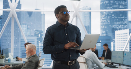 Aufkleber - African American Financial Analyst Walking In Skyscraper Office With Diverse Employees In Downtown. Succeful Black Man Using Laptop Computer To Go Through Tasks And Business Mettings In Hedge Fund.