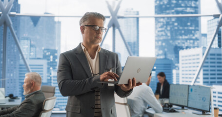 Aufkleber - Succeful Caucasian Businessman Walking In Modern Office With Diverse Employees In Downtown Skyscraper. Middle-Aged Male Entrepreneur Using Laptop Computer In E-commerce Company Workspace.