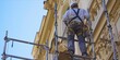© ParinApril - Construction worker on scaffolding in front of a building facade.