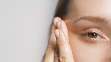 A girl woman massages herself around the eyes using facial oil. At home Beauty care. Close up