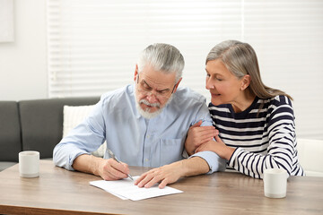 Wall Mural - Senior couple signing Last Will and Testament indoors