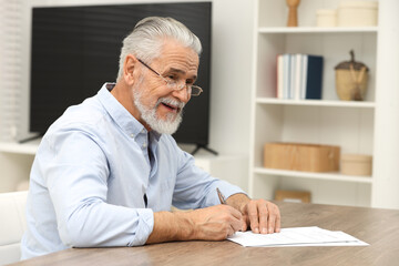 Poster - Senior man signing Last Will and Testament at wooden table indoors. Space for text