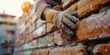 Fototapeta  - Closeup Hands Adjusting Bricks in Wall. Worker's hand placing a brick on a crumbling wall.