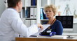 Doctor interviewing elderly woman patient in clinic office. Taking medical anamnesis concept