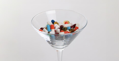 Wall Mural - Glass with lot of multicolored medical capsules on white background closeup. Polypharmacy concept