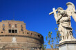 Castel Sant'Angelo - Mausoleum of Hadrian located on the bank of the River Tiber with white stone angel monument holding a crucifix, against a bright blue sky, Rome, Italy