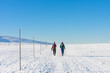Two tourists walking in krkonose mountains, path from Silesian House to Meadow Hut, winter morning. Along the road are wooden long bars, tourist markings for winter season.