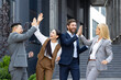 © Liubomir - A young interracial business team is happy about a successful deal and partnership. A group of men and women stand outside an office center and high five each other, congratulating on victory.