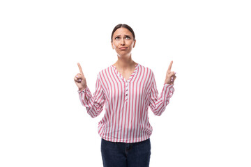 Wall Mural - young brunette office worker woman dressed in a shirt points with her hands to the space for advertising