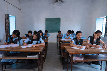 Group of indian village students in school uniform sitting in classroom doing homework, studying. Education concept