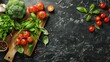 A variety of fresh vegetables, herbs and tomatoes arranged on a dark marble slate background.