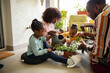 © Marko Geber - Young family watering plants and flowers on the balcony of their apartment