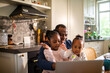 © Marko Geber - Father and daughters having fun with a laptop in the kitchen