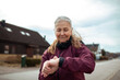 © Marko Geber - Senior woman checking smartwatch during outdoor exercise