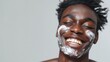 Portrait of a African man his cheeks covered in cream, smiles while covering his eyes during a skincare routine against clean background with space for text, Generative AI.