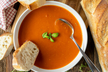 Wall Mural - Homemade tomato soup with baguette on a deep plate with spoon